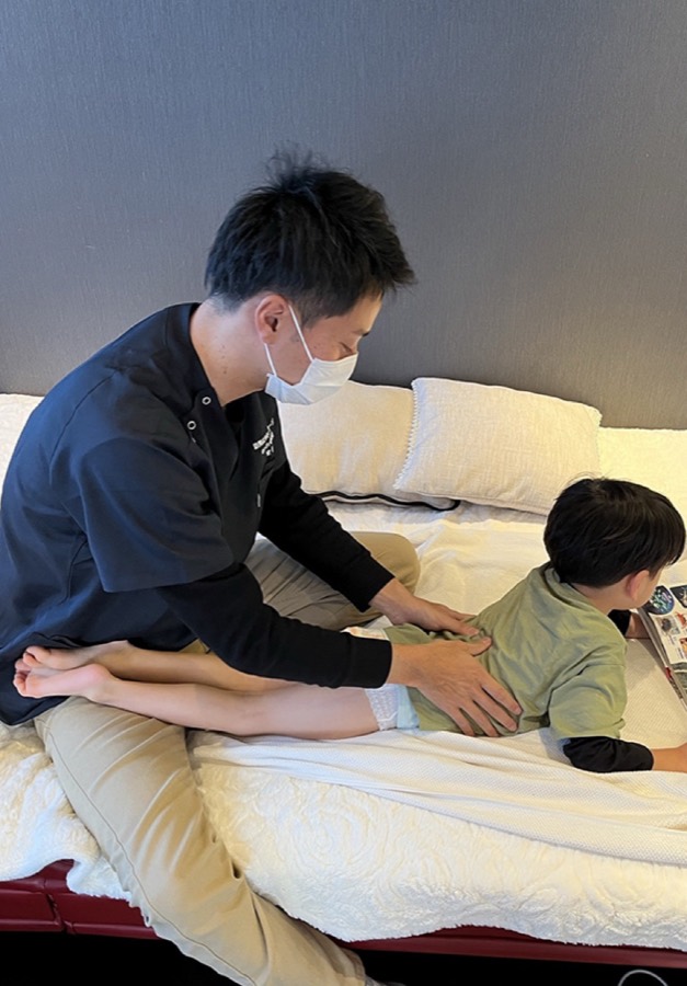 ベッドで絵本を読みながら施術を受けるお子さま